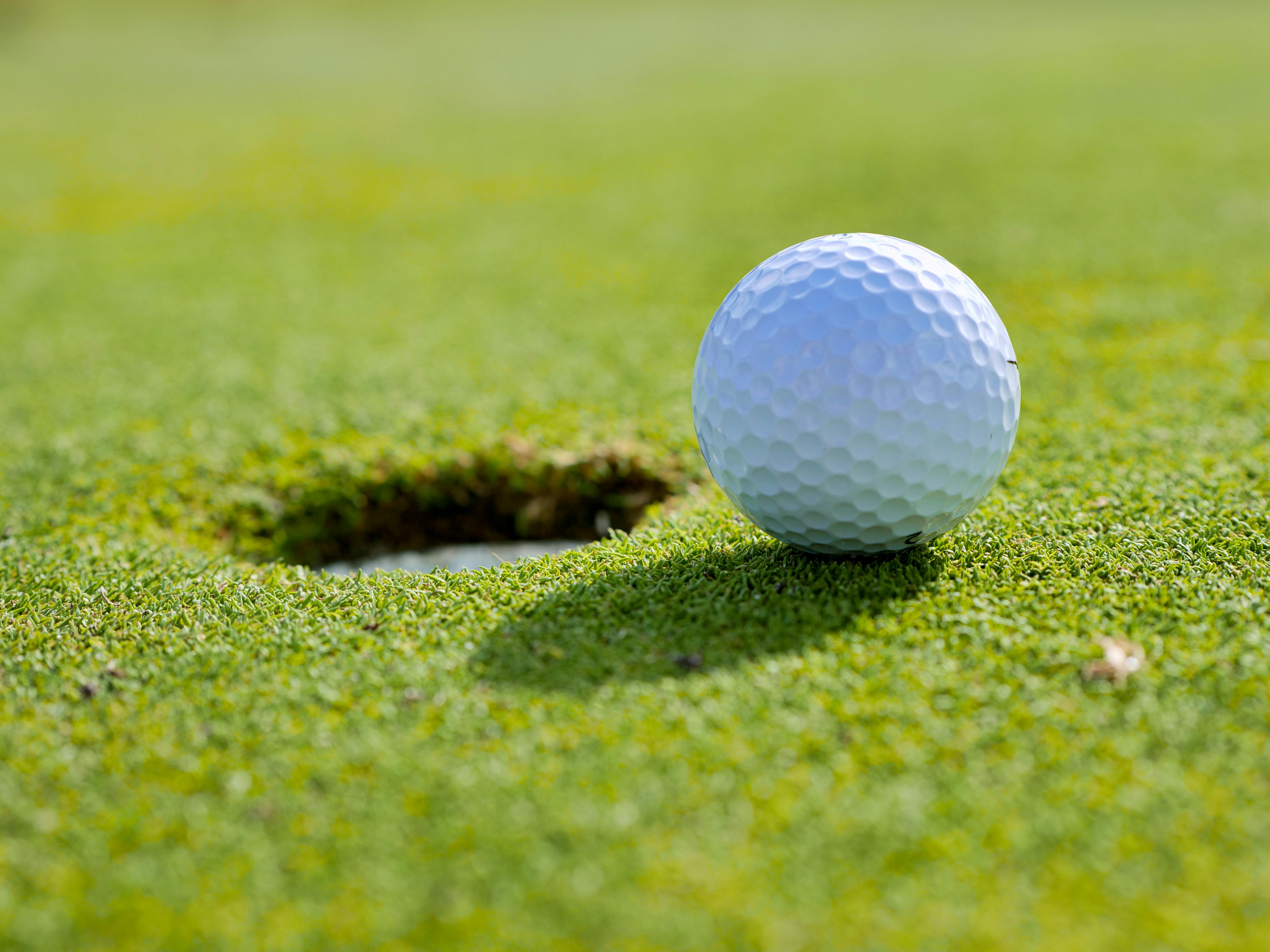 Image of golf ball on tee on grass.