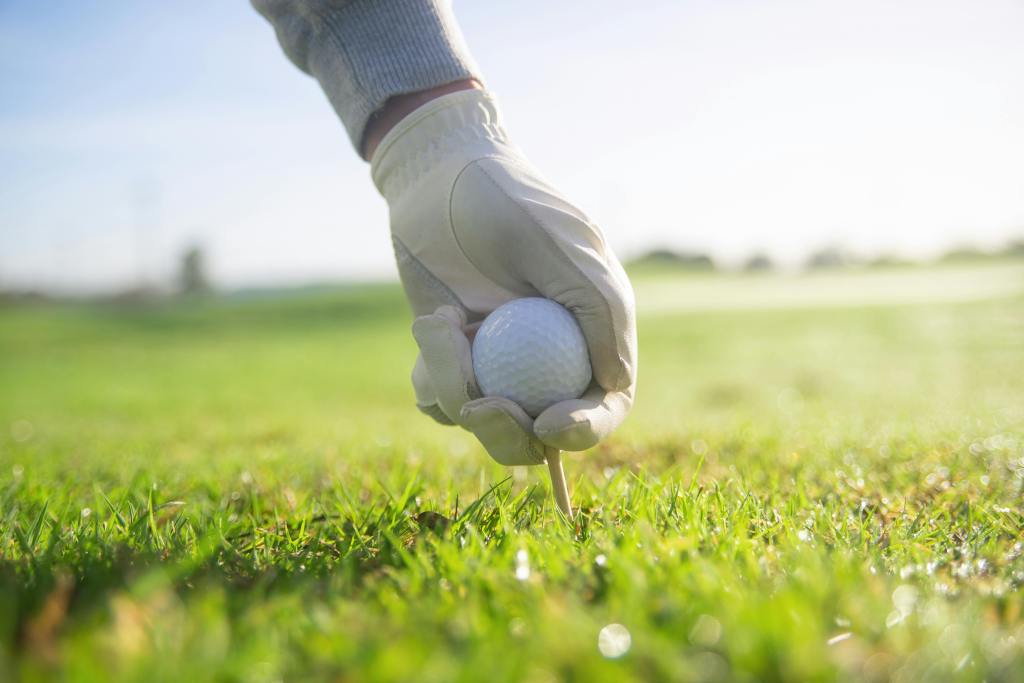 Golfer placing golf ball on tee 